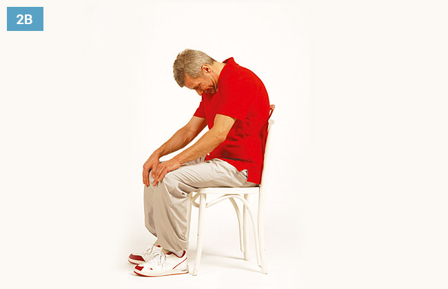 Ćwiczenie w siadzie na krześle, ręce oparte na kolanach, pochylona głowa do przodu